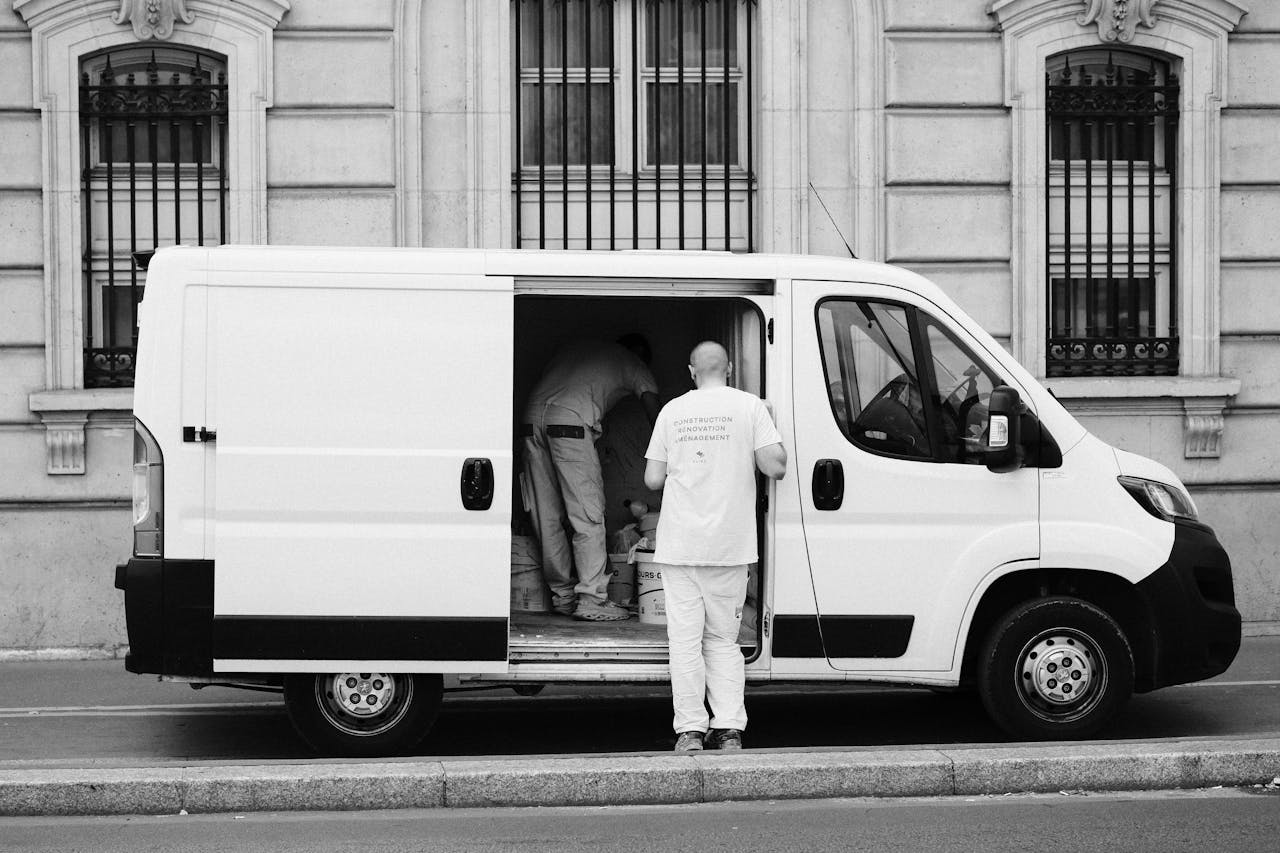 Monochrome image of a delivery van with workers, showcasing urban logistics.